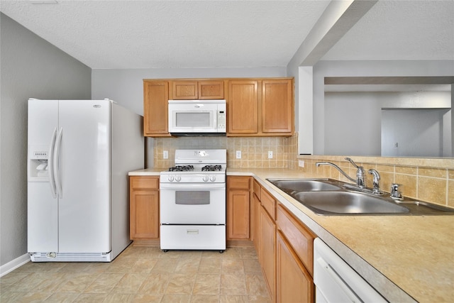 kitchen with white appliances, a sink, tasteful backsplash, light countertops, and a textured ceiling