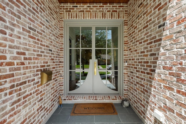 view of exterior entry with brick siding and french doors