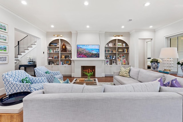 living room featuring ornamental molding, recessed lighting, wood finished floors, built in features, and stairs