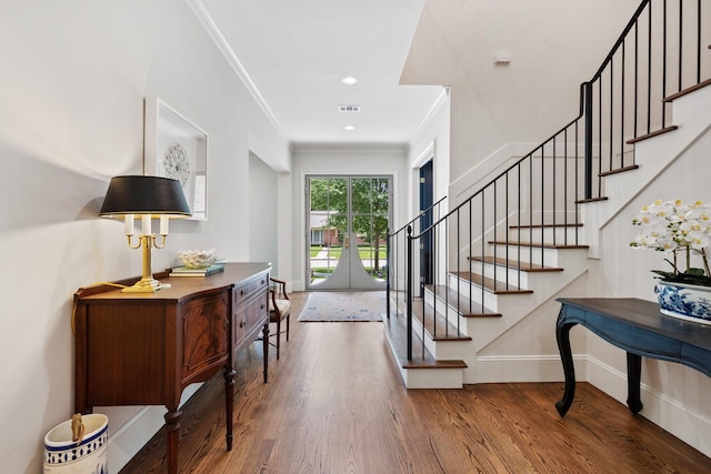 foyer featuring wood finished floors, stairway, baseboards, crown molding, and recessed lighting