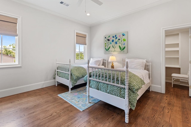 bedroom with multiple windows, wood finished floors, baseboards, and ornamental molding