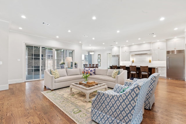 living area featuring crown molding, light wood-style floors, recessed lighting, and baseboards