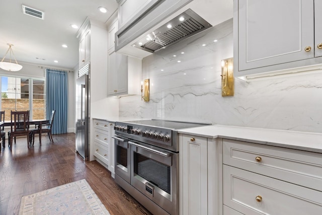 kitchen featuring premium appliances, custom exhaust hood, decorative backsplash, dark wood finished floors, and white cabinetry