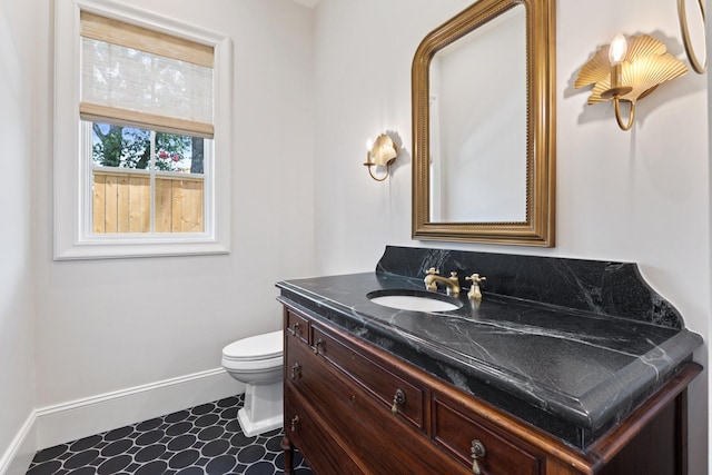 bathroom with baseboards, vanity, and toilet