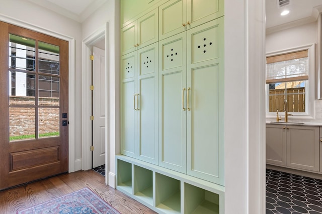 mudroom with crown molding, a sink, wood finished floors, and baseboards