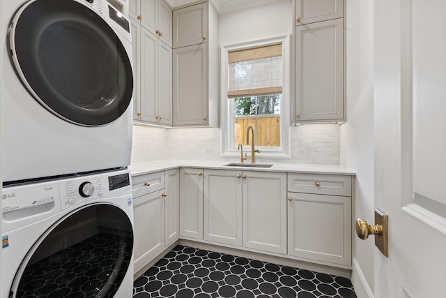 clothes washing area featuring stacked washer / drying machine and cabinet space