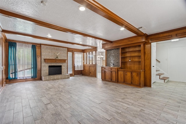 15623 Ensenada Dr, Houston, TX 77083 - unfurnished living room with a textured ceiling, beamed ceiling, stairway, a fireplace, and light wood-type flooring