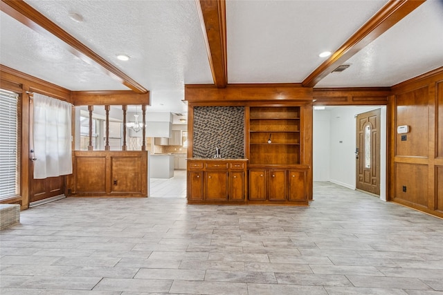 15623 Ensenada Dr, Houston, TX 77083 - unfurnished living room with beamed ceiling, a textured ceiling, light wood-style flooring, wood walls, and a sink