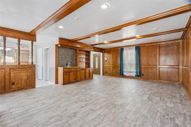 15623 Ensenada Dr, Houston, TX 77083 - unfurnished living room featuring a textured ceiling, beamed ceiling, light wood-type flooring, wood walls, and baseboards