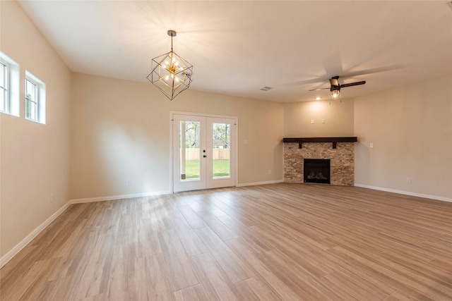 14606 W 6th St, Santa Fe, TX 77517 - unfurnished living room featuring light wood-type flooring, ceiling fan, a chandelier, baseboards, and a stone fireplace