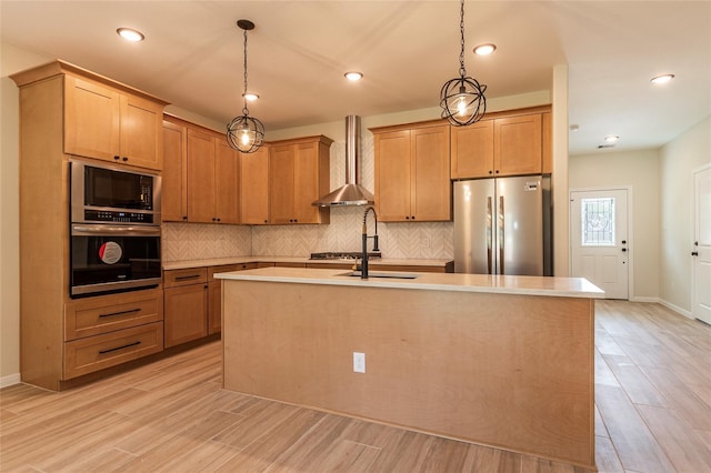 14606 W 6th St, Santa Fe, TX 77517 - kitchen featuring appliances with stainless steel finishes, wall chimney range hood, tasteful backsplash, light wood-type flooring, and a sink