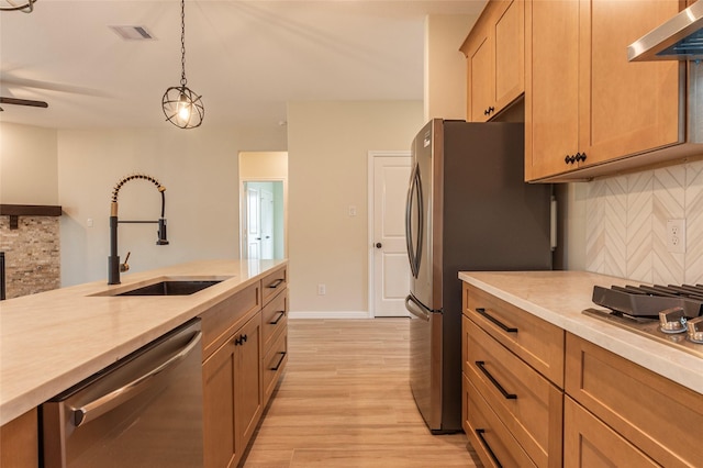 14606 W 6th St, Santa Fe, TX 77517 - kitchen featuring appliances with stainless steel finishes, wall chimney exhaust hood, a sink, light countertops, and light wood-style flooring