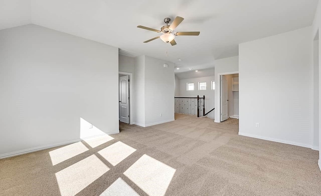 spare room with light carpet, a ceiling fan, and baseboards