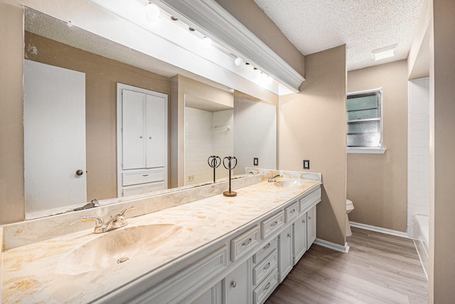 3823 Fernglade Dr, Houston, TX 77068 - bathroom with wood finished floors, double vanity, baseboards, toilet, and a textured ceiling
