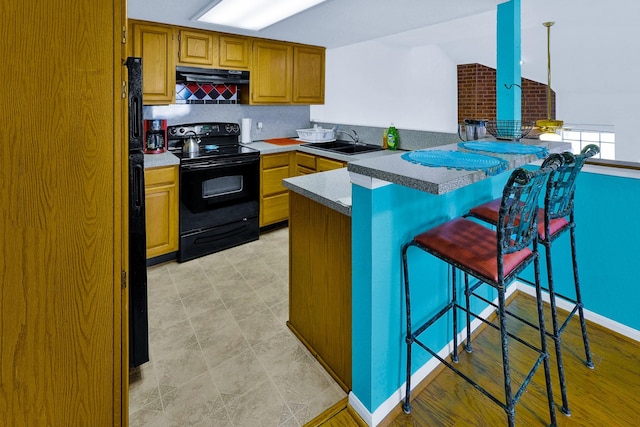 3100 75th St Unit 5, Galveston, TX 77551 - kitchen with black range with electric cooktop, a sink, a kitchen bar, a peninsula, and under cabinet range hood