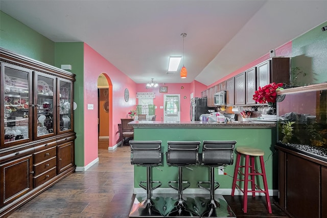 2902 Back Bay Brook Trl, Houston, TX 77045 - kitchen featuring arched walkways, stainless steel microwave, dark wood-style flooring, fridge, and a breakfast bar area