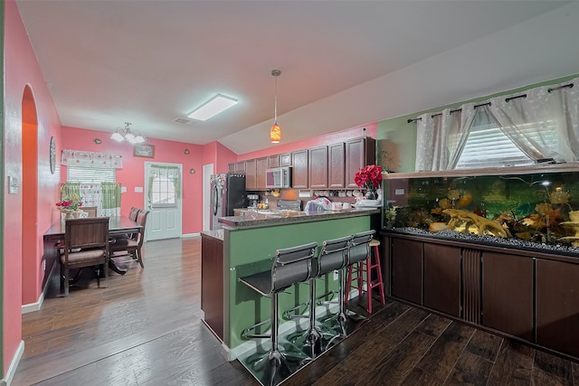 2902 Back Bay Brook Trl, Houston, TX 77045 - kitchen featuring appliances with stainless steel finishes, vaulted ceiling, dark wood finished floors, a peninsula, and arched walkways