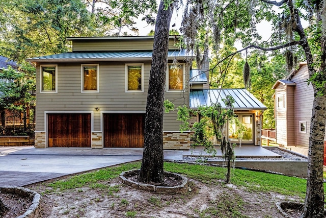 888 Cedar Ln, Livingston, TX 77351 - view of front of home featuring a standing seam roof, a garage, concrete driveway, metal roof, and stone siding