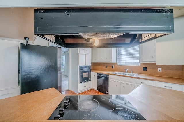 15714 Pebble Bend Dr, Houston, TX 77068 - kitchen featuring black appliances, a sink, under cabinet range hood, white cabinetry, and light countertops