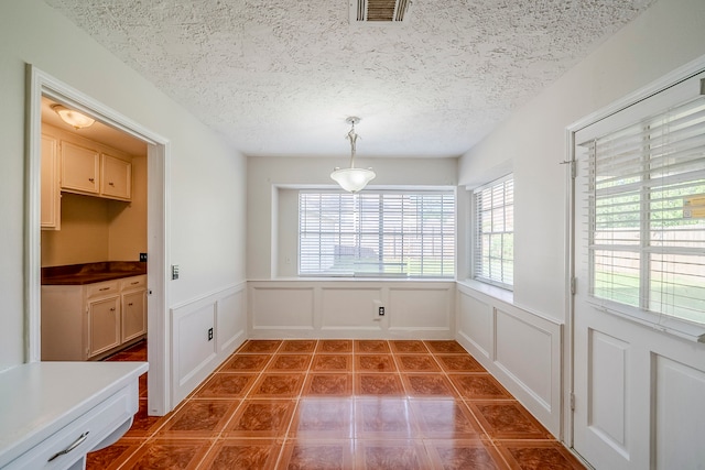 15714 Pebble Bend Dr, Houston, TX 77068 - unfurnished dining area featuring a decorative wall, wainscoting, a textured ceiling, and tile patterned flooring