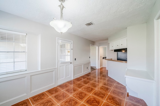 15714 Pebble Bend Dr, Houston, TX 77068 - unfurnished dining area with a decorative wall, a textured ceiling, and a wainscoted wall