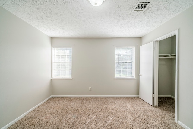 15714 Pebble Bend Dr, Houston, TX 77068 - unfurnished bedroom with carpet flooring, multiple windows, a spacious closet, and a textured ceiling