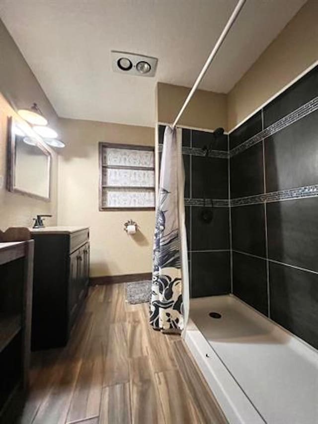 1005 Lamar St, Vidor, TX 77662 - bathroom featuring wood finished floors, tiled shower, vanity, and baseboards