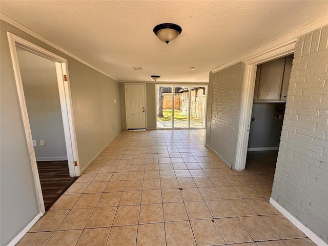 738 Beachcomber Ln, Houston, TX 77062 - empty room featuring ornamental molding, a textured ceiling, light tile patterned floors, baseboards, and brick wall
