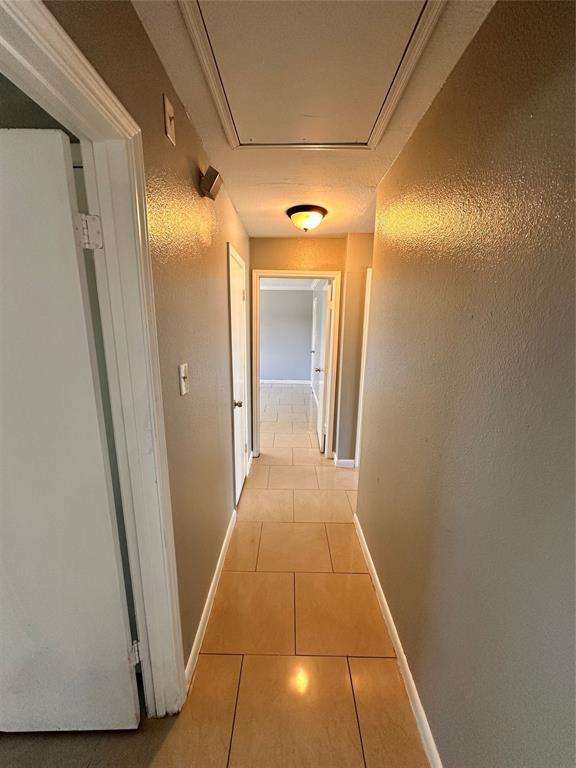 738 Beachcomber Ln, Houston, TX 77062 - corridor featuring light tile patterned floors, baseboards, and attic access