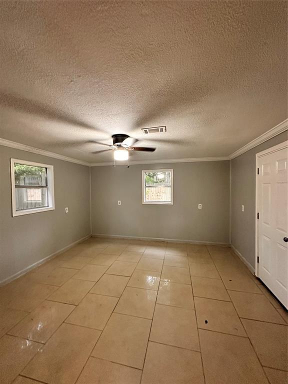 738 Beachcomber Ln, Houston, TX 77062 - empty room with healthy amount of natural light, crown molding, a ceiling fan, a textured ceiling, and light tile patterned floors