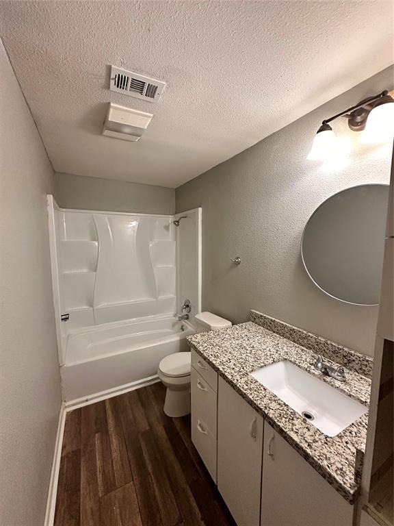 738 Beachcomber Ln, Houston, TX 77062 - bathroom with a textured ceiling, wood finished floors, tub / shower combination, vanity, and toilet