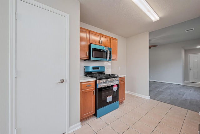 2706 Star Peak Dr, Houston, TX 77088 - kitchen featuring stainless steel range with gas stovetop, light countertops, light tile patterned flooring, baseboards, and a textured ceiling