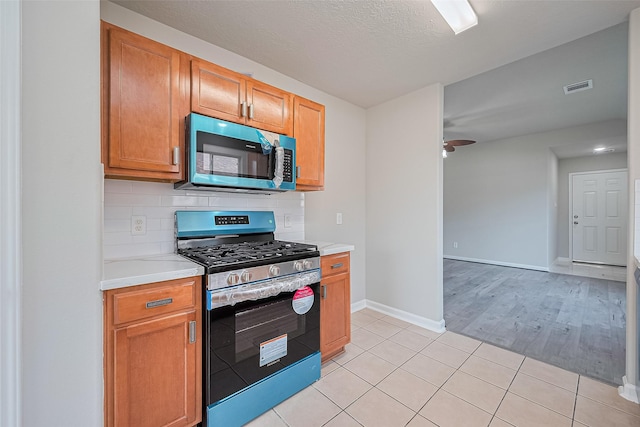 2706 Star Peak Dr, Houston, TX 77088 - kitchen with gas stove, light countertops, light tile patterned flooring, baseboards, and a ceiling fan