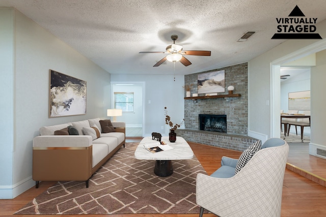 16466 Mandate Dr, Houston, TX 77049 - living area with wood finished floors, a fireplace, a ceiling fan, a textured ceiling, and baseboards