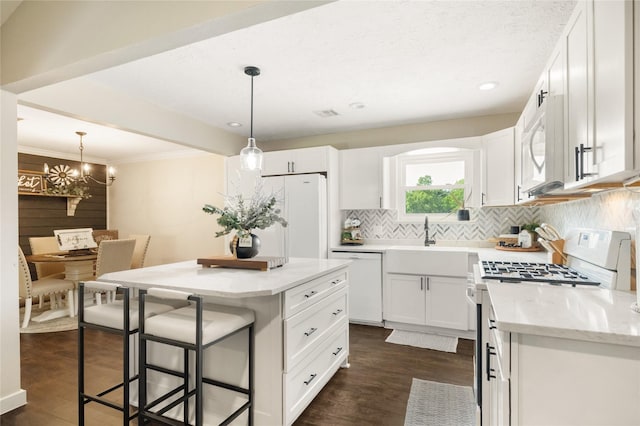 1209 Kansas Ave S, Anahuac, TX 77514 - kitchen featuring white appliances, dark wood finished floors, a sink, backsplash, and a kitchen breakfast bar