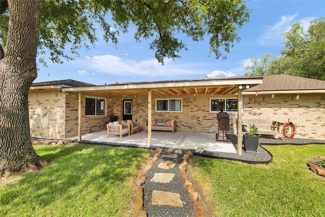 1209 Kansas Ave S, Anahuac, TX 77514 - back of house featuring brick siding, a patio, and a yard