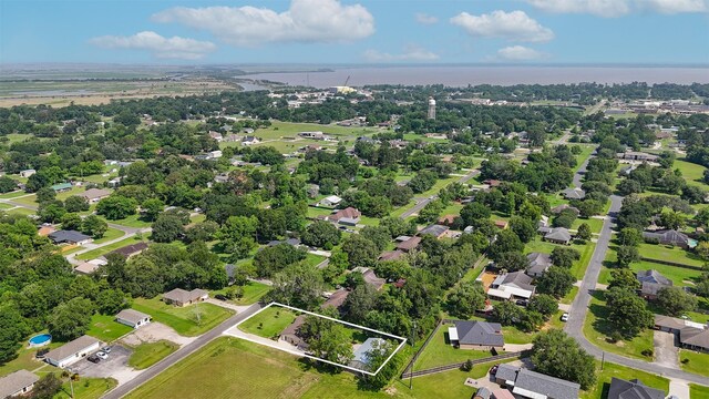 1209 Kansas Ave S, Anahuac, TX 77514 - aerial perspective of suburban area featuring property parcel outlined and a tree filled landscape