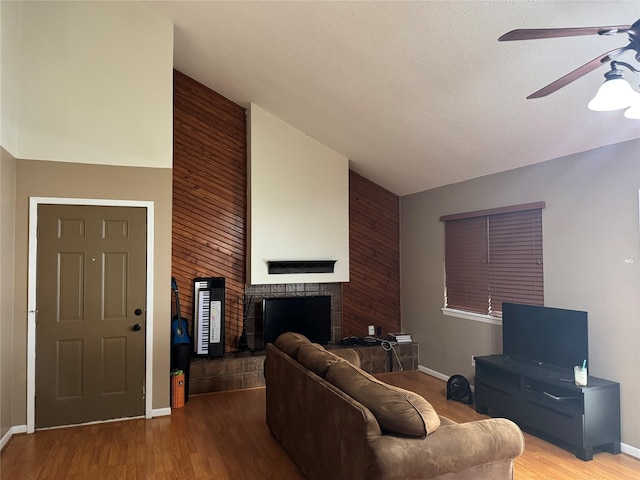 618 Hickory St, Huntsville, TX 77320 - living room featuring ceiling fan, wood walls, a fireplace, high vaulted ceiling, and wood finished floors