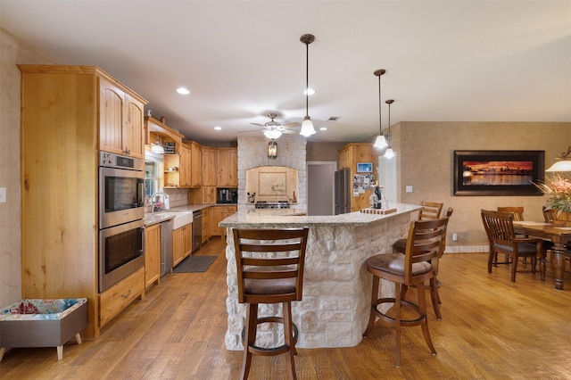 4430 Fm 546, Princeton, TX 75407 - kitchen with light wood-style flooring, ceiling fan, a breakfast bar, light stone countertops, and appliances with stainless steel finishes