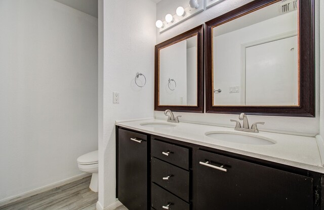 716 Bering Dr Unit 30, Houston, TX 77057 - bathroom with wood finished floors, toilet, double vanity, and baseboards