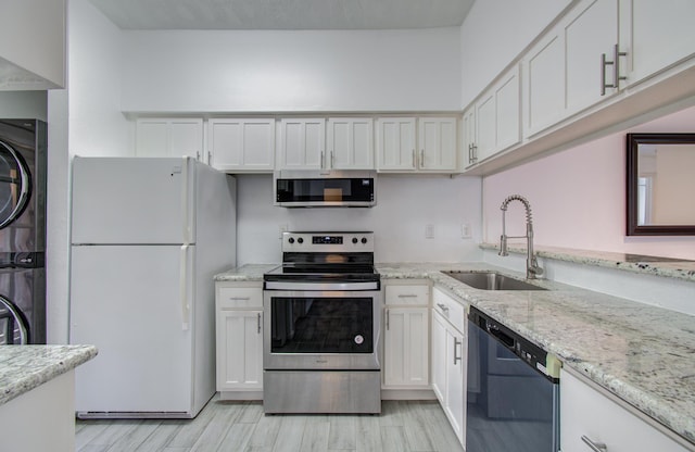 716 Bering Dr Unit 30, Houston, TX 77057 - kitchen featuring appliances with stainless steel finishes, a sink, stacked washer and clothes dryer, light wood finished floors, and white cabinets