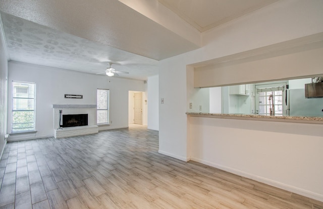 716 Bering Dr Unit 30, Houston, TX 77057 - unfurnished living room with a ceiling fan, light wood-type flooring, a fireplace with raised hearth, and baseboards