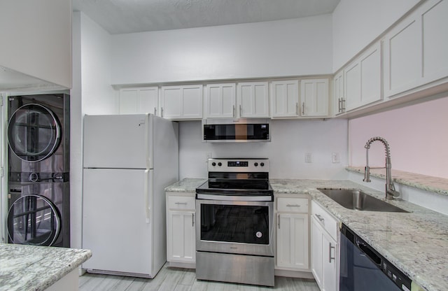 716 Bering Dr Unit 30, Houston, TX 77057 - kitchen featuring stainless steel appliances, stacked washing machine and dryer, a sink, light stone counters, and white cabinets