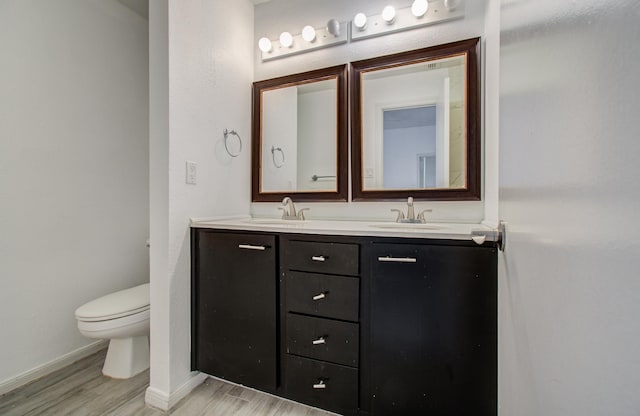 716 Bering Dr Unit 30, Houston, TX 77057 - bathroom featuring wood finished floors, double vanity, toilet, and baseboards