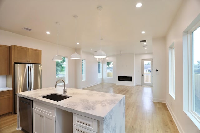 510 E 37th St, Houston, TX 77022 - kitchen featuring a sink, stainless steel appliances, light wood-style flooring, hanging light fixtures, and a kitchen island with sink