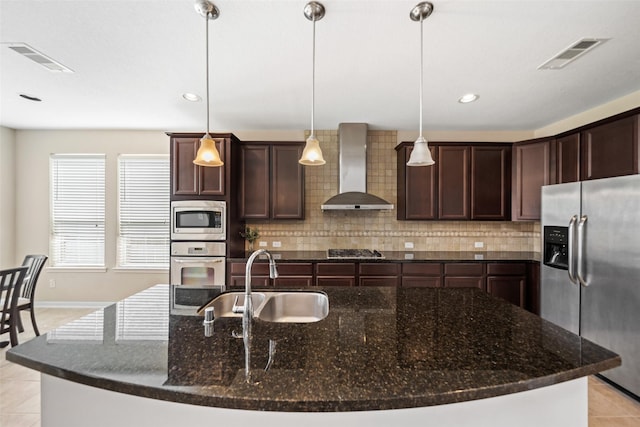 kitchen featuring appliances with stainless steel finishes, wall chimney exhaust hood, light tile patterned floors, a sink, and backsplash