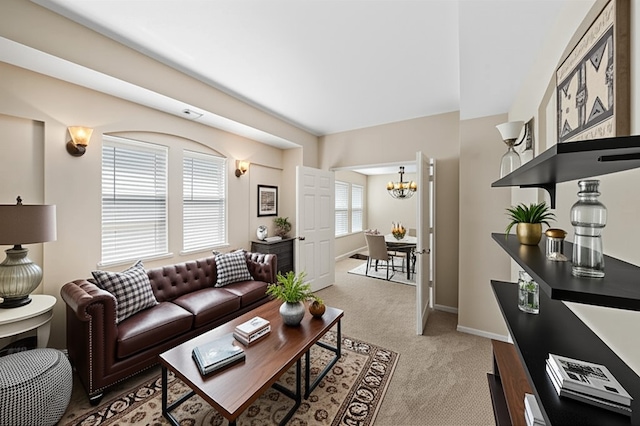 living room with a chandelier, light carpet, and baseboards