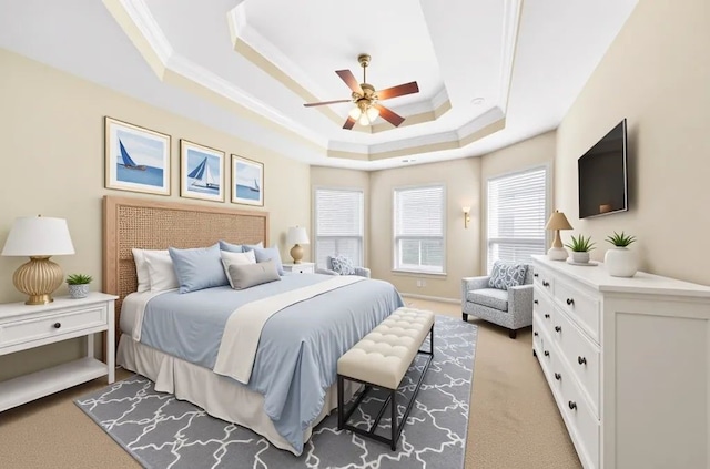 bedroom featuring a tray ceiling, crown molding, light carpet, and ceiling fan