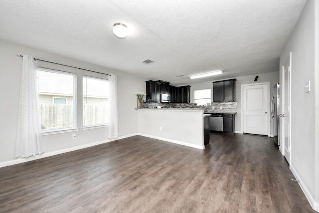 696 Rd 5105, Cleveland, TX 77327 - kitchen with appliances with stainless steel finishes, a textured ceiling, a peninsula, dark wood-type flooring, and decorative backsplash