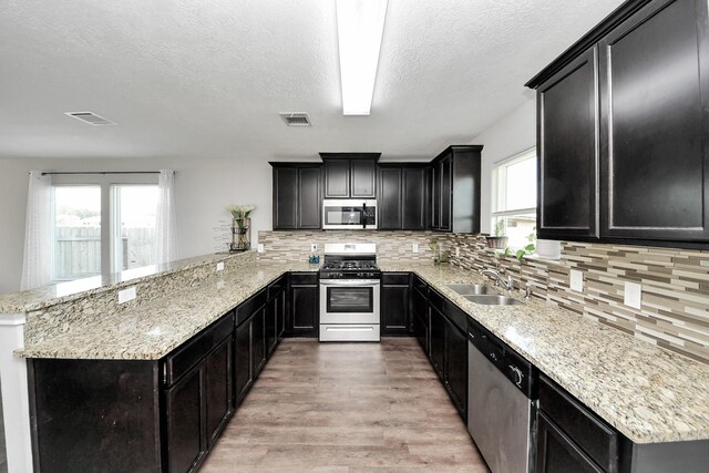 696 Rd 5105, Cleveland, TX 77327 - kitchen featuring appliances with stainless steel finishes, a sink, dark cabinets, light wood-style flooring, and a textured ceiling